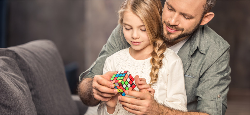 Father and daughter playing with large Rubik's cube puzzle